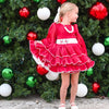 Young girl in a red dress standing in front of a Christmas tree with colorful ornaments.