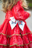 Red dress with white embroidery and a decorative bow worn by a child.