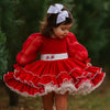 Young girl in a red dress with white trim and white boots standing outdoors.